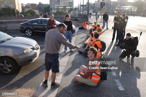 Motorist argues with activists from the group "Last Generation" who had glued themselves on the asphalt to block an intersection on an offramp of the...