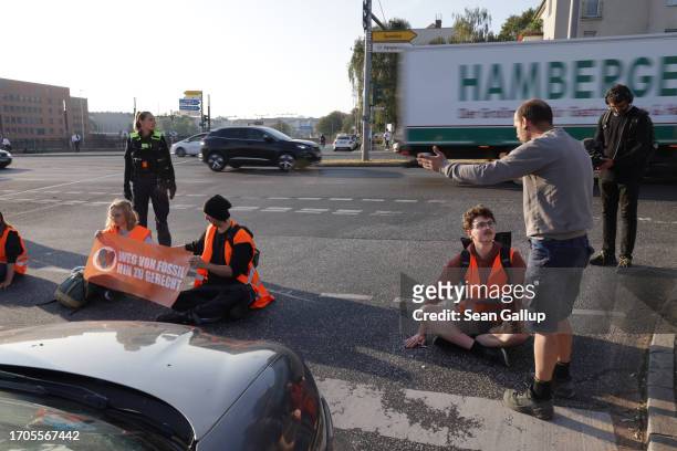 Motorist argues with activists from the group "Last Generation" who had glued themselves on the asphalt to block an intersection on an offramp of the...