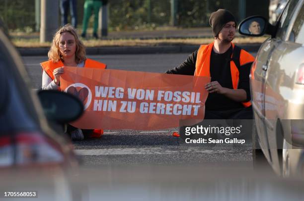 Activists from the group "Last Generation" , who have glued themselves to the asphalt, block an intersection on an offramp of the A100 highway on...