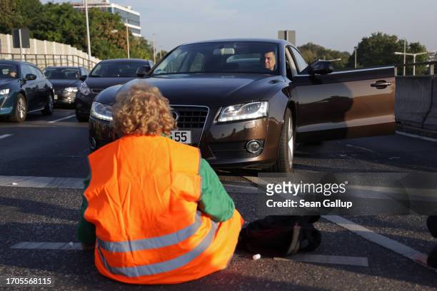An activist from the group "Last Generation" , who have glued himself to the asphalt, blocks an intersection on an offramp of the A100 highway on...