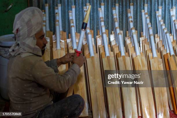 Worker wrap rubber onto unfinished cricket bats in a bat factory on October 3, 2023 in Halmullah, 50 km, south of Srinagar, Indian administered...
