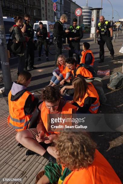 Police stand among climate activists from the group "Last Generation" who had glued themselves to the asphalt to block an intersection on an offramp...