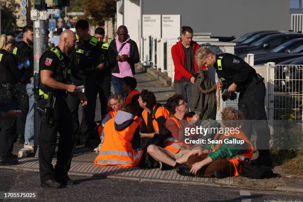 Police stand among climate activists from the group "Last Generation" who had glued themselves to the asphalt to block an intersection on an offramp...
