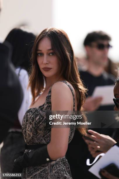 Alycia Debnam-Carey is seen outside Dior show wearing a beige and black prinnted Dior dress with shoulder straps and black leather gloves during the...