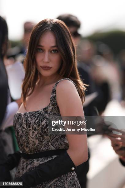 Alycia Debnam-Carey is seen outside Dior show wearing a beige and black prinnted Dior dress with shoulder straps and black leather gloves during the...