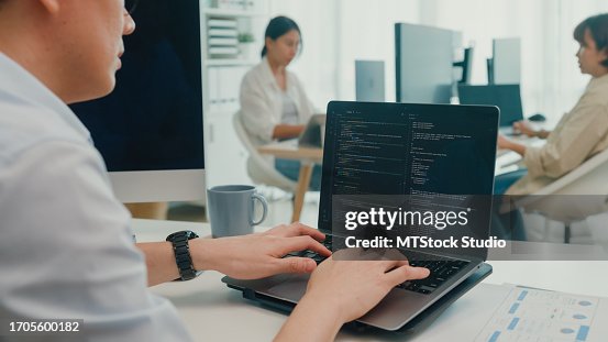 Closeup group of Asian people software developers using computer to write code sitting at desk with multiple screens at office. Programmer development. Closeup group of Asian people software developers using computer to write code sitting at desk with multiple screens at office. Programmer development.