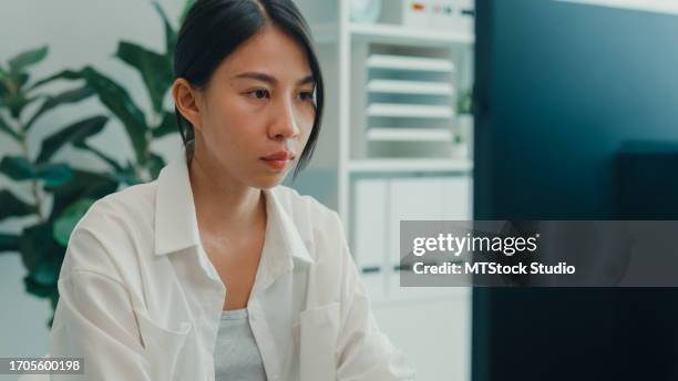 closeup young asian woman software developers using computer to write code sitting at desk with multiple screens work at office. programmer development. - female programmer stock pictures, royalty-free photos & images