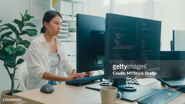 de jeunes développeuses de logiciels asiatiques utilisant un ordinateur pour écrire du code assises à un bureau avec plusieurs écrans travaillent au bureau. développement de programmeurs. - java stock photos et images de collection