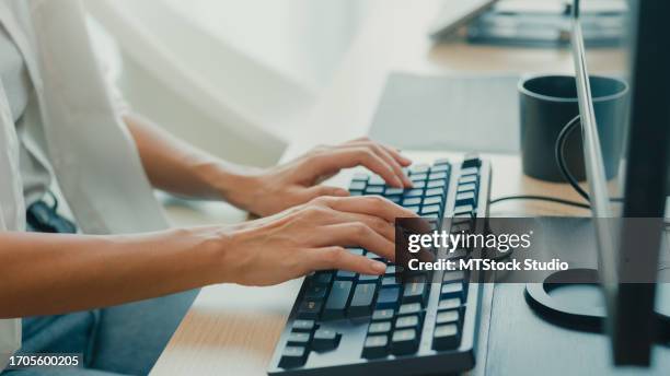 closeup young asian woman software developers using computer to write code sitting at desk with multiple screens work at office. programmer development. - application programming interface stockfoto's en -beelden