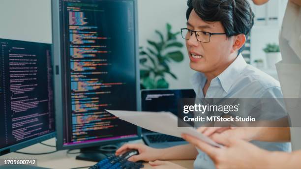 closeup group of asian people software developers using computer to write code sitting at desk with multiple screens at office. programmer development. - java code stock pictures, royalty-free photos & images