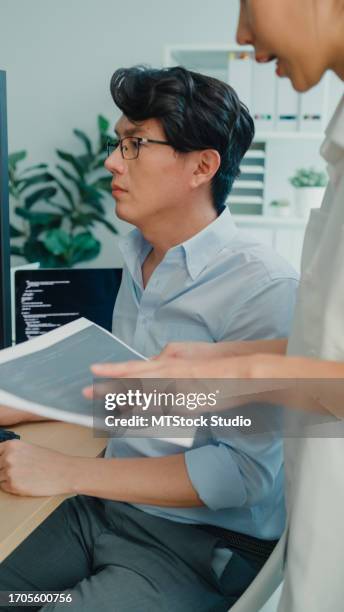 group of asian people software developers using computer to write code sitting at desk with multiple screens at office. programmer development. vertical screen. - application programming interface stockfoto's en -beelden