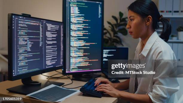 giovani donne asiatiche che sviluppano software che usano il computer per scrivere codice seduti alla scrivania con più schermi lavorano in ufficio di notte. sviluppo programmatore. - programmazione televisiva foto e immagini stock