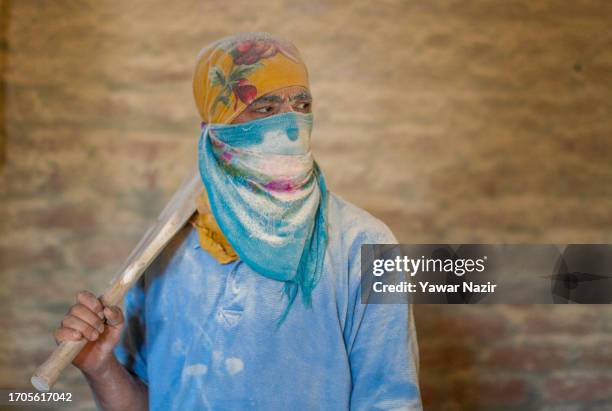 Amidst sawdust, a worker holds an unfinished cricket bat, waiting for electricity to resume near the buffing machine in the bat factory on October 3,...