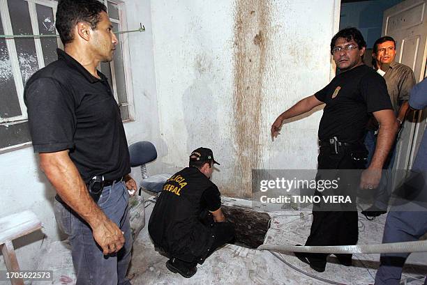 Brazilian Federal Police agent points at the entrance of the tunnel dug by the Central Bank robbers 08 August in Fortaleza, northeastern Brazil....