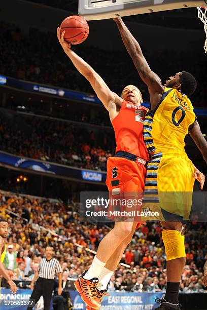 Brandon Triche of the Syracuse Orange drives to the basket against Jamil Wilson of the Marquette Golden Eagles during the East Regional Round Final...