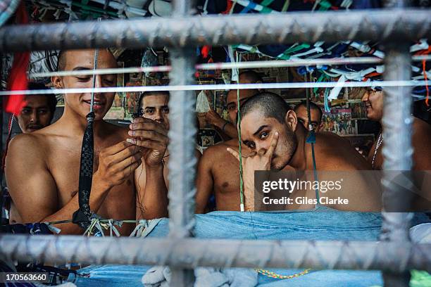 An MS-13 gang members gestures the Devils Head insignia inside one of the three 'gang cages' in the Quezaltepeque police station May 20, 2013 in San...