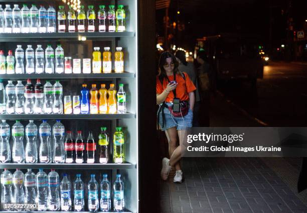 Girl with a phone in her hand is standing near a refrigerator with drinks on September 5, 2023 in Kyiv, Ukraine. Residents of the city continue to go...