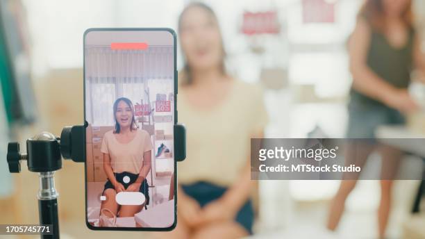 closeup of young asian women live streaming on phone show new collection shoes to customer at shop. sme small business e-commerce. - stativ bildbanksfoton och bilder