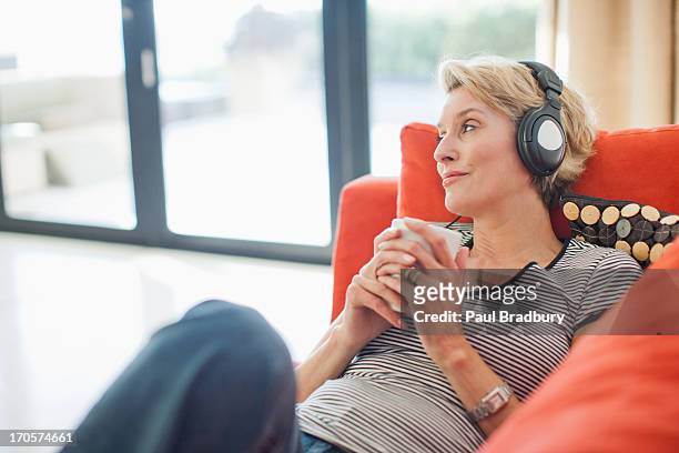 woman drinking coffee and listening to headphones - listening music stock pictures, royalty-free photos & images