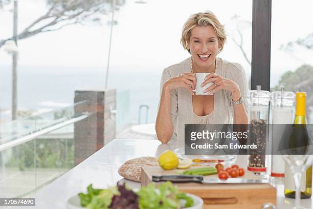 woman drinking coffee in kitchen - mature adult cooking stock pictures, royalty-free photos & images