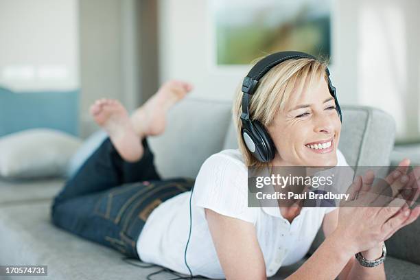 frau leg dich auf sofa bei musik kopfhörer - headphones woman stock-fotos und bilder