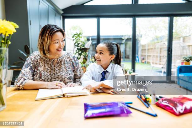 asian mother doing homework with elementary school daughter - multitasking student stock pictures, royalty-free photos & images