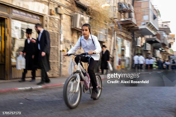 An Ultra-Orthodox Jewish boy rides a bicycle ahead of the holiday in the Ultra-Orthodox neighborhood of Mea Shearim on September 27, 2023 in...