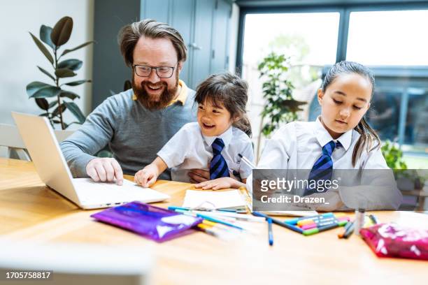 mixed asian family with kids, father doing homework with daughters, using laptop and notepad - multitasking student stock pictures, royalty-free photos & images