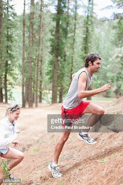 couple climbing hill in forest - uphill stockfoto's en -beelden