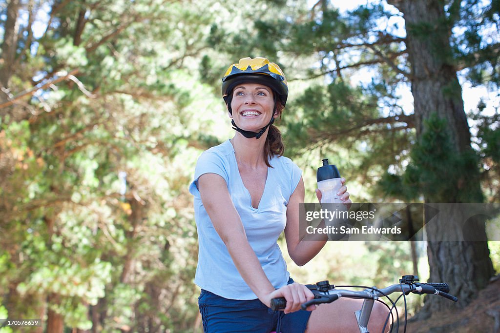 Woman on bicycle drinking water in forest