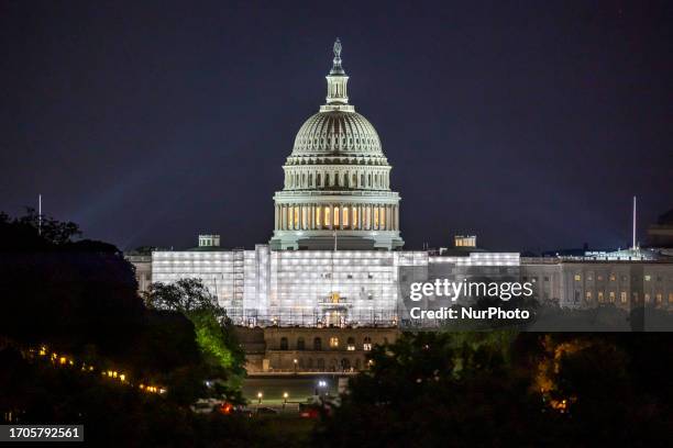 The United States Capitol with the illuminated Dome with city lights seen during the night behind the Washington Monument with local people, visitors...