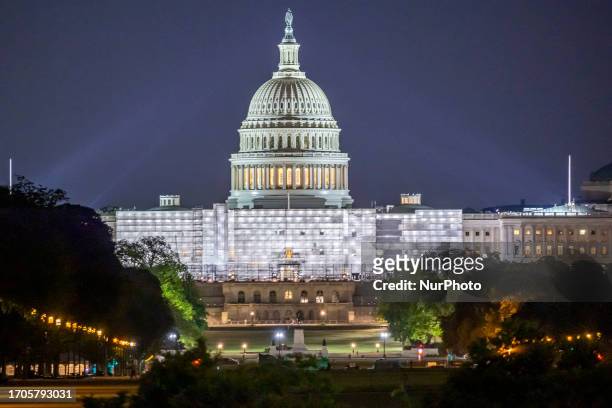 The United States Capitol with the illuminated Dome with city lights seen during the night behind the Washington Monument with local people, visitors...