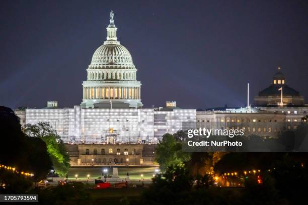 The United States Capitol with the illuminated Dome with city lights seen during the night behind the Washington Monument with local people, visitors...