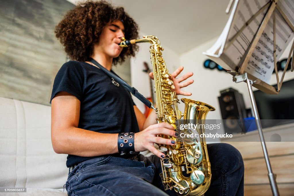 Un adolescent joue du saxophone à la maison