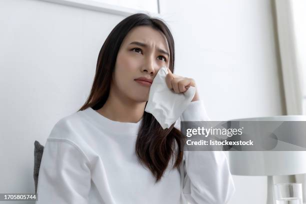 young pretty asian girl sitting on a cozy sofa in the living room and watching tv. - film screening room stock pictures, royalty-free photos & images