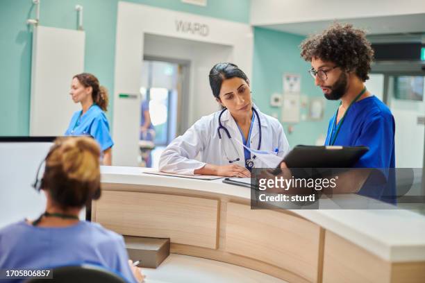 ward doctor discusses ward case load - nurse station stock pictures, royalty-free photos & images