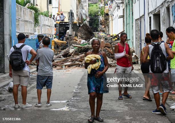 Neighbours watch as rescuers work at an apartment block following a collapse, in Havana, on October 4, 2023. At least one person has died, a...