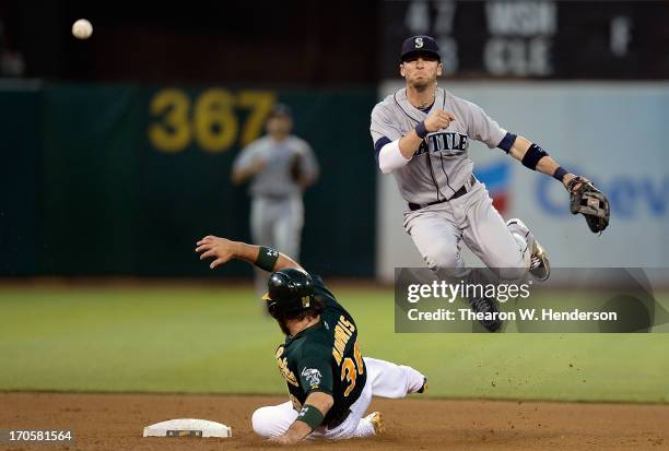 Brendan Ryan of the Seattle Mariners gets his throw off but not in time to complete the double-play while avoiding the slide of Derek Norris of the...