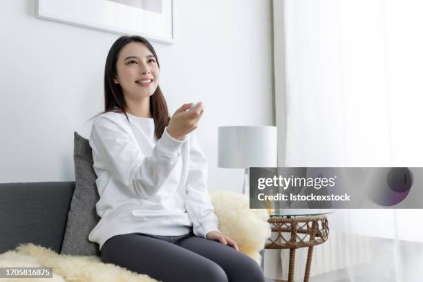 asian woman on sofa watching a tv - film screening room stock pictures, royalty-free photos & images