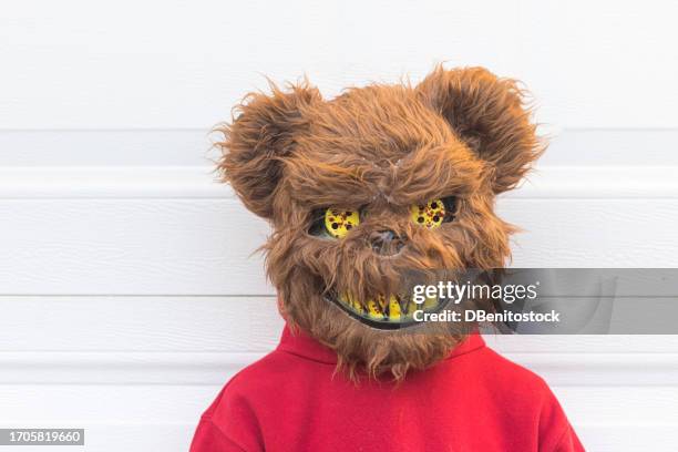 young person in a halloween costume wearing a killer bear mask over a white garage door. concept of day of the dead, fear, terror, halloween, scare and trick or treat. - bear suit 個照片及圖片檔