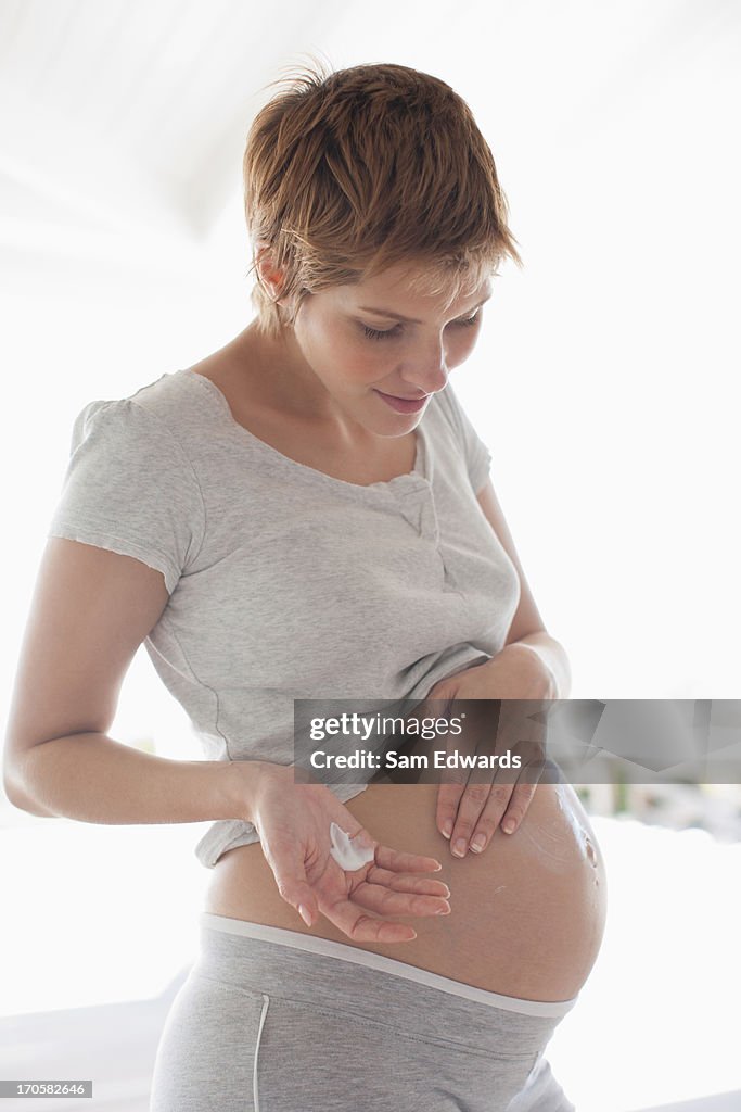 Pregnant woman rubbing lotion into stomach