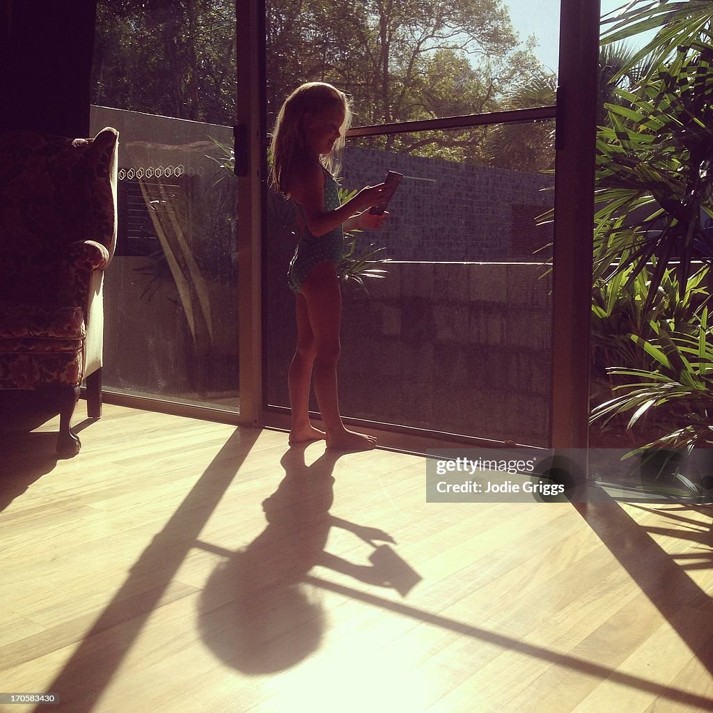 Young child standing by window in morning sun