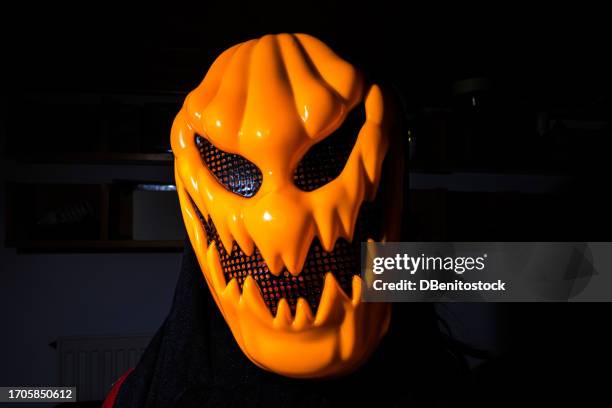 person wearing scary halloween pumpkin face over low key, with side light and dark background. concept of day of the dead, fear, terror, halloween, scare, cinematic and trick or treat. - ugly lips stock pictures, royalty-free photos & images