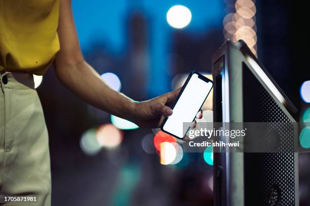 in the nighttime, an asian woman in the city is using her mobile phone to make a payment for parking, embracing the concepts of digital wallets and diverse payment methods. - cidade inteligente imagens e fotografias de stock