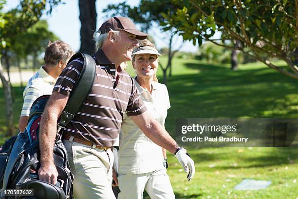 couple d'âge mûr portant sacs de golf - golfeur photos et images de collection