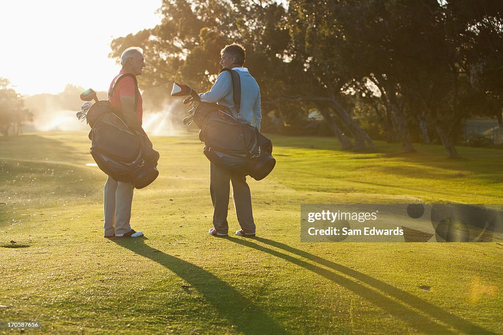 Men carrying golf bags on golf course