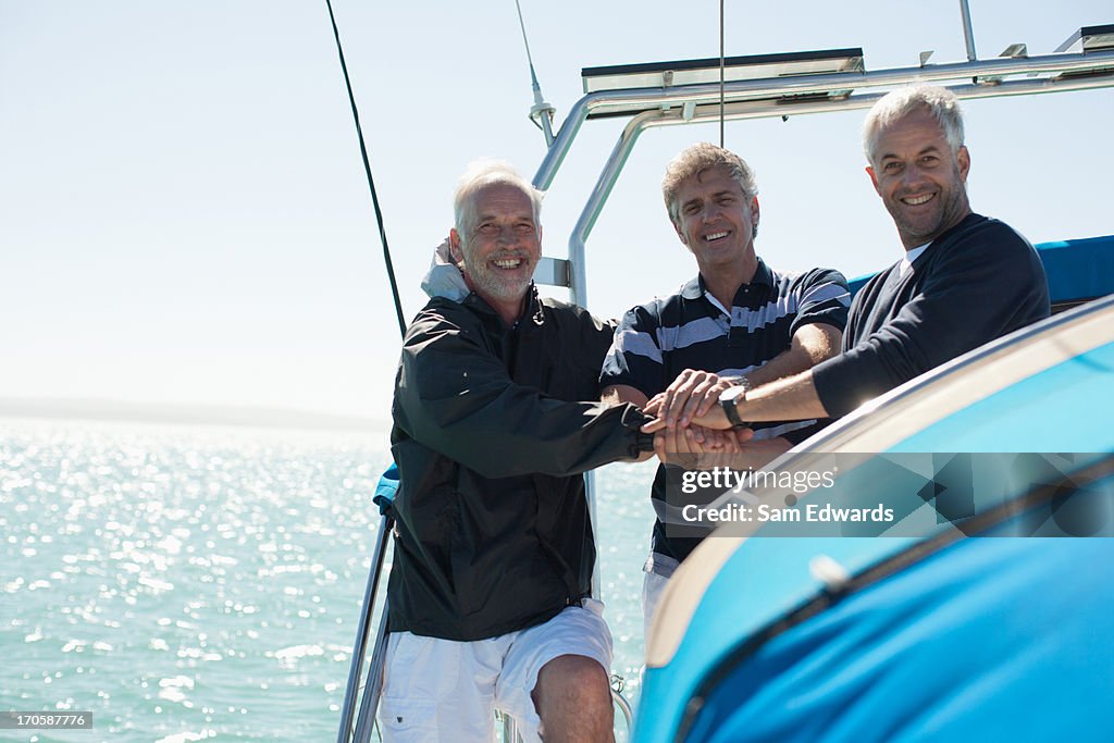 Friends clasping hands on deck of boat