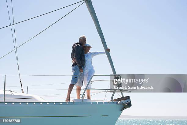mature couple hugging on deck of sailboat - yacht luxury nautical vessel stock pictures, royalty-free photos & images