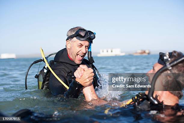 hombres en las actividades de engranaje agarrar de la mano - buceo con equipo fotografías e imágenes de stock