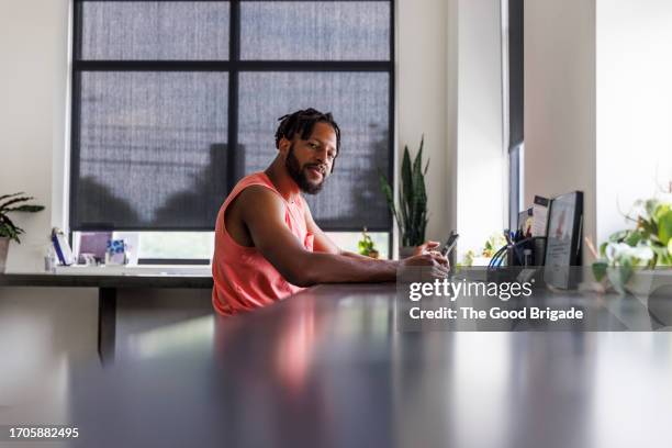 portrait of young entrepreneur sitting in office with digital tablet - tank top stock pictures, royalty-free photos & images